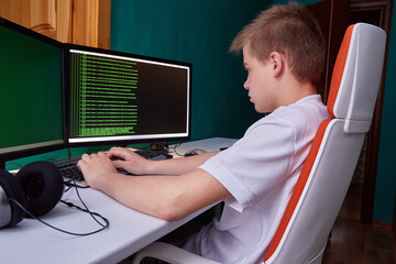A young programmer guy prints the program code on the computer monitor screen. The concept of computer security, technology development and young professionals