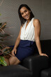 © Alejandro - sitting on a sofa a beautiful young latin woman with short straight hair posing, in the background various colorful plants, studio and beauty