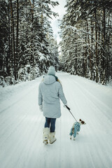 a girl with a dog in the winter forest