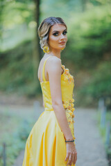 Canvas Print - Vertical shot of a young blonde female posing in a yellow floral evening dress