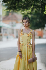 Canvas Print - Vertical shot of a young blonde female posing in a yellow floral evening dress