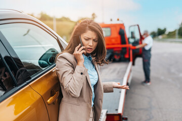 Wall Mural - Elegant middle age business woman calling someone while towing service helping her on the road. Roadside assistance concept..