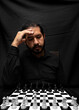 © Narayan - latin man with beard worried with chess game, chess concept