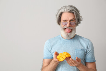 Canvas Print - Senior man with cut mango on light background