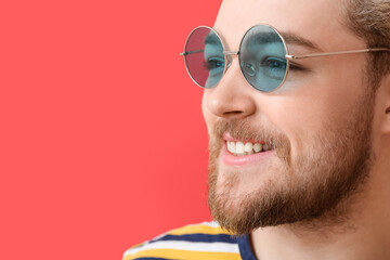 Canvas Print - Young man with stylish sunglasses on color background, closeup