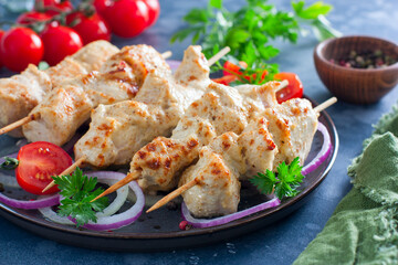 Wall Mural - Chicken breast kebab baked in the oven on wooden skewers on a plate, horizontal