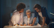 © TommyStockProject - Team of multiethnic architects working on construction plans late in dark office