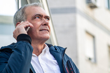 Wall Mural - adult attractive man using mobile phone and holding laptop on the street