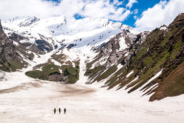 three hikers look at the view of the himalayas on the beas kund trek in northern india