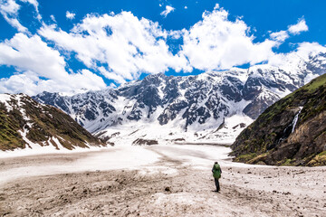 a lone hiker looks at the view of the himalayas on the beas kund trek in northern india