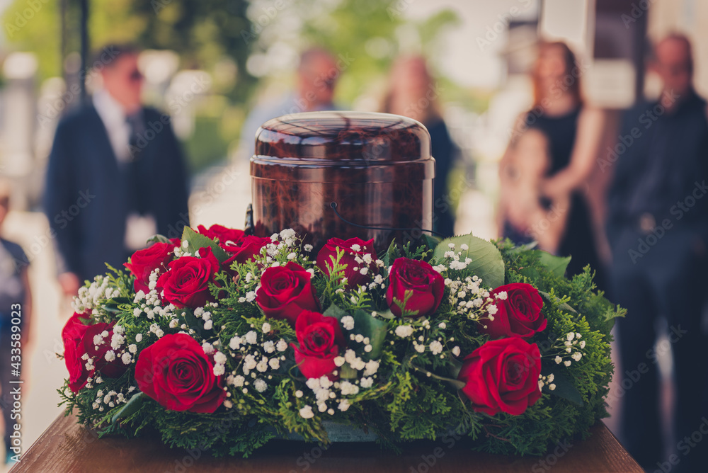 Funerary urn with ashes of dead and flowers at funeral. - obrazy, fototapety, plakaty 