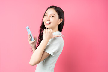 Poster - Young Asian woman holding phone in hand and pointing back