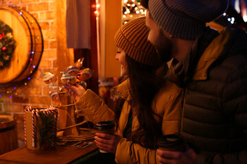 Canvas Print - Lovely couple with cups of hot drinks spending time together at Christmas fair