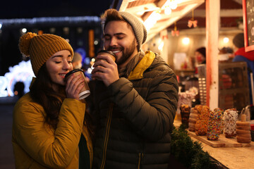 Canvas Print - Lovely couple with cups of hot drinks spending time together at Christmas fair