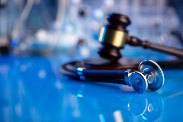 Medical law concept. Gavel and stethoscope on the glass table. Blue light.