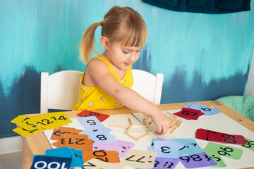 Little caucasian girl studying numbers and math in the classroom, stylish interior for home education, preschool child education, home schooling
