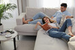 © New Africa - Happy couple with book on sofa in living room