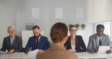 back view of female applicant during job interview talking to diverse employers