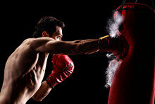 Strong Muscular Man Punching A Bag With Boxing Gloves
