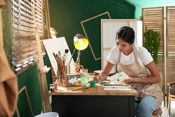 Canvas Print - Young woman drawing leaf with watercolors at table indoors