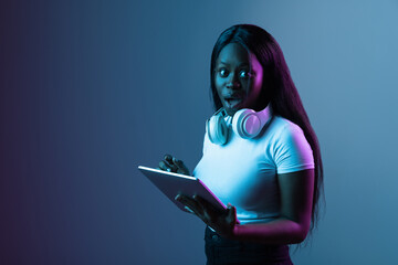 Portrait of young beautiful girl isolated over dark background in neon