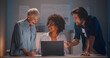 © TommyStockProject - Group of happy diverse business people team working on project using laptop in office at night