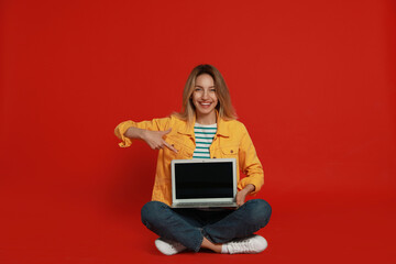 Sticker - Young woman with modern laptop on red background