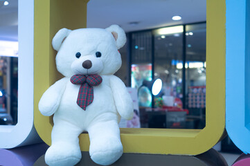 A lovely, adorable, sweet white teddy bear sitting in bad mood in the metal frame in department store for kids and interested people to take photo with