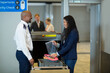 © Wavebreak Media - Smiling diverse male airport security officer checking womans luggage