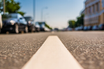 Summer in the city, the street with parked cars. Close up view from the level of the dividing line