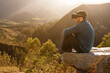 © Alberto Menendez/ADDICTIVE STOCK - Side view of male traveler in VR glasses interacting with virtual reality while sitting on hill in mountainous terrain at sunset