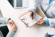 © Alvaro Sanchez/ADDICTIVE STOCK - Cropped unrecognizable elderly male doctor in uniform filling form on clipboard at table against unrecognizable woman during checkup in clinic