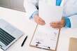 © Alvaro Sanchez/ADDICTIVE STOCK - Top view of crop unrecognizable male doctor working at table with paper form and netbook against stethoscope in hospital