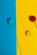 From Above Of Small Woolen Thread Balls Representing Lollies On Sticks On Blue And Yellow Background