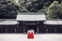 Back View Of Unrecognizable People In Traditional Kimono Standing Outside Of Ancient Meiji Shrine Temple Located In Mountains In Shibuya In Tokyo, Japan