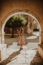 Back View Unrecognizable Female In Stylish Summer Dress Standing Near Medieval Building Arch On Sunny Summer Day In Heraklion Milos