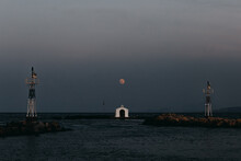 Scenic View Of Small White St Nickolas Church Located On Islet Under Dark Sky With Luminous Moon At Dusk