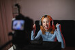 © Dani Navarro/ADDICTIVE STOCK - Smiling female gamer in headphones recording video on professional camera for social media blog