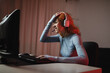 © Dani Navarro/ADDICTIVE STOCK - Side view of worried female gamer in headphones playing video game while sitting at table with keyboard