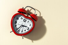 Red Metal Alarm Clock In Shape Of Heart Placed On Vibrant Beige Background In Studio