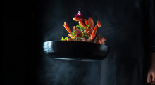 Chef Cooks Shrimp In A Pan With Vegetables. Cooking Seafood, Healthy Vegetarian Food And Food On A Black Background. Freezing In Motion. Free Advertising Space