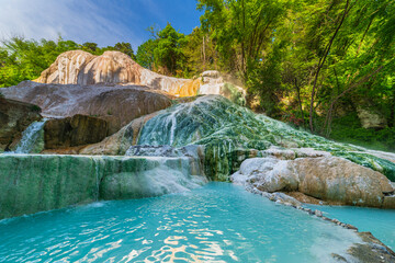 Geothermal pool and hot spring in Tuscany, Italy. Bagni San Filippo natural thermal waterfall in the morning with no people. The White Whale amidst forest.