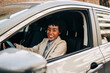© Jake Jakab/ADDICTIVE STOCK - Side view of cheerful African American female driver in fashionable outfit smiling while driving modern automobile on the street