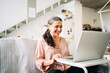 © Jake Jakab/ADDICTIVE STOCK - Positive middle aged female sitting on couch and sending air kiss while having video chat on netbook in modern apartment