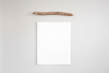 Wall Mural - Minimalist vertical poster frame mockup template hanging from a piece of old driftwood on a neutral coloured wall. 