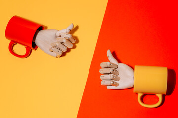 Creative ornamental wooden hand with thumbs up inside colorful mug on yellow and red background in studio