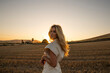 © Laura Bauza/ADDICTIVE STOCK - Peaceful female in elegant dress standing on dry field in rural area and looking at camera