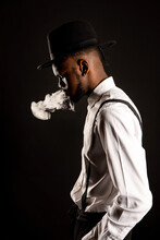 Side View Of Masculine African American Male In White Shirt And Hat Exhaling Vapor While Smoking E Cigarette