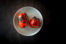 Top View Of Delicious Whole Grilled Red Peppers In Round Shaped Ceramic Bowl On Dark Background