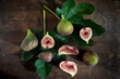 © Nitin Kapoor/ADDICTIVE STOCK - Top view of whole and cut figs with juicy pulp on green foliage with veins on wooden surface